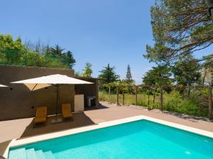 a swimming pool with two chairs and an umbrella at Finca Fuente Laurel in Arucas