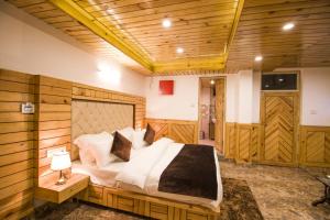 a bedroom with a large bed in a room with wooden walls at AYUSHKAMA COTTAGE #Naddi Sunset Point#Free Parking#cricket stadium8 km#Mcleodganj 2 km- Bhagsunag 4 km in Dharamshala