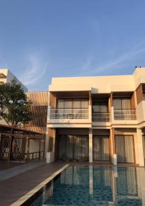 a building with a swimming pool in front of it at Sea Suphan Villa in Ban Hua Phrong