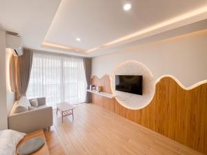 a living room with a couch and a tv on a wall at Sea Suphan Villa in Ban Hua Phrong