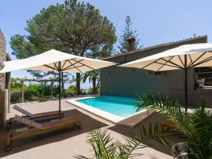 a swimming pool with two umbrellas and two lounge chairs at Finca Fuente Laurel in Arucas