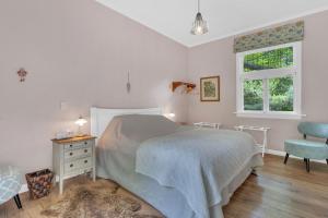 a bedroom with a bed and a chair and a window at Rose Cottage - Tranquil retreat in Tinui
