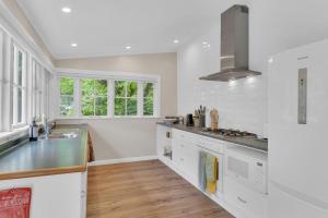 a kitchen with white cabinets and a stove top oven at Rose Cottage - Tranquil retreat in Tinui