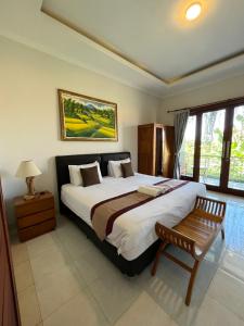 a bedroom with a large bed and a wooden chair at Surya Guest House Sanur in Sanur +99 photos
