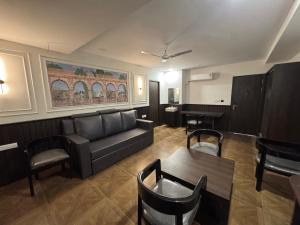a living room with a couch and a table and chairs at HOTEL SNR AURORa in Guntūr