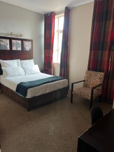 a bedroom with a bed and a chair and a window at Warm & Cozy Diamonds Hotel in Johannesburg