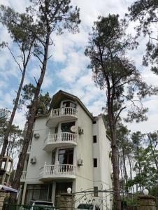 a white building with a balcony and trees at Shekvetili Babi in Shekhvetili