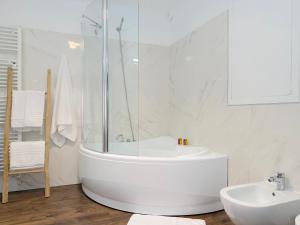 a white bathroom with a tub and a sink at Ugo Jacuzzi Apartment in Bologna