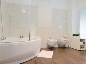 a white bathroom with a tub and a toilet at Ugo Jacuzzi Apartment in Bologna