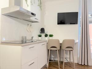 a kitchen with white cabinets and a sink and two stools at Ugo Jacuzzi Apartment in Bologna