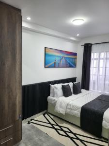 a bedroom with a bed and a painting on the wall at Private 2BR Bungalow in Quiet Green Gated Estate in Nairobi