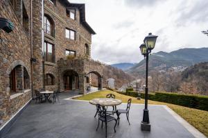 a patio with a table and chairs and a building at Abba Xalet Suites Hotel in Sispony