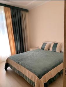a bedroom with a large bed with a window at Дом у Айбека in Tamga