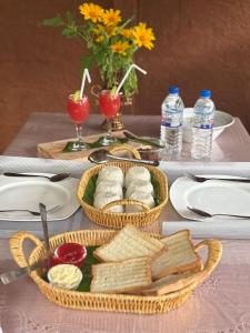 a table with two baskets of bread and glasses of water at Nature Nest Cabana in Sigiriya