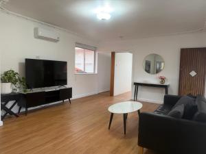 a living room with a couch and a flat screen tv at Como Beach Apartment 2 in Perth