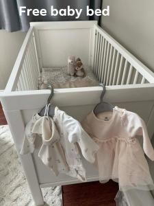 a crib with white baby clothes and stuffed animals in it at Bright & Spacious Apartment by the Sea, Free Parking, 10min to Airport, 12min to Ålesund in Ytterland