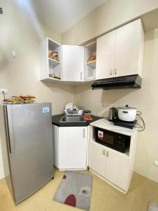 a small kitchen with white cabinets and a refrigerator at 1008 T2 Avida Tower Atria Comfy Cozy in Iloilo City