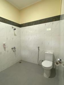 a bathroom with a white toilet in a room at SADAMA Cottage in Tuktuk Siadong