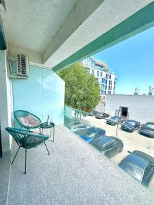 a balcony with chairs and a table and cars in a parking lot at Mario Summerland Property in Mamaia