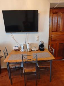 a wooden table with chairs and a television on a wall at Kastri in Kythira