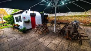 a patio with tables and chairs and an umbrella at The George and Dragon Inn in Long Melford