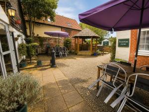 a patio with tables and chairs and a purple umbrella at The George and Dragon Inn in Long Melford