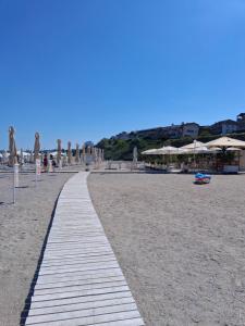 a walkway on a sandy beach with umbrellas at Apartament DelyMar in Agigea