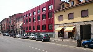 un edificio rosso su una strada cittadina con auto parcheggiate di Igiban Hotel a Milano