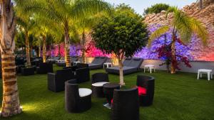 a garden with chairs and palm trees and a wall with purple flowers at Corfu Hotel in Ayia Napa