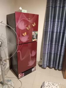 a room with a fan and a refrigerator with flowers on it at One Private Room Near Dhaka Airport in Dhaka