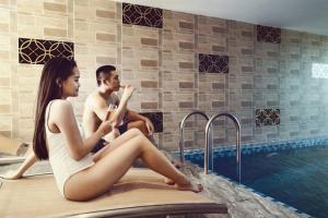 a man and woman sitting next to a swimming pool at Ruby Luxury Hotel in Nha Trang