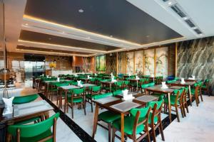 a restaurant with wooden tables and green chairs at Ruby Luxury Hotel in Nha Trang