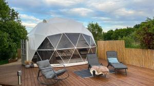 a gazebo on a wooden deck with chairs at Saare Glamping Dome House in Salme
