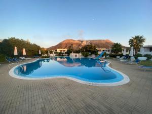 a large swimming pool with chairs and a resort at Villetta Darsena con piscina gratuita dal 18 Luglio al 30 Agosto in Vulcano