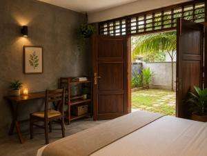 a bedroom with a bed and a desk and a door at Ceylon Stays Hiriketiya in Nilwella