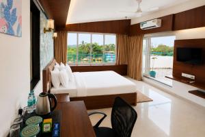 a hotel room with a bed and a desk and a television at Hotel H F at Assagao North Goa in Assagao