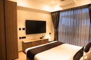 a hotel room with a bed and a flat screen tv at The Vilton in Raipur