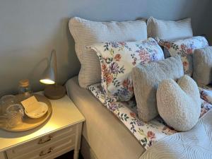 a bed with pillows and a table with a lamp at Bright & Spacious Apartment by the Sea, Free Parking, 10min to Airport, 12min to Ålesund in Ytterland