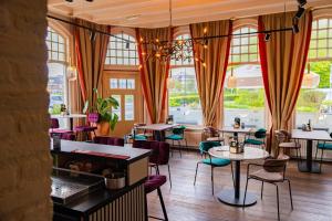 a restaurant with tables and chairs and windows at Hotel Restaurant Noordooster in Delfzijl