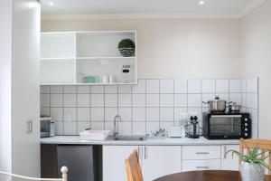 a white kitchen with a sink and a microwave at 12 On York Guesthouse in Bloemfontein