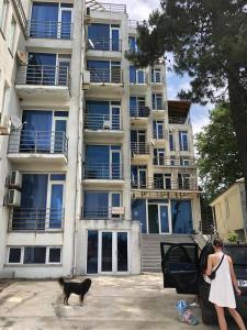 a woman walking a black cat in front of a building at Квартира in Ureki