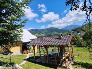 a house with a gazebo with mountains in the background at Casuta Mariei, Borsa,Maramures in Borşa
