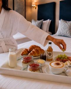 a tray of food on a bed with a woman reaching for a tray of food at Powerscourt Arms Hotel in Enniskerry