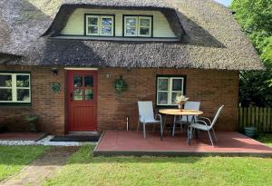 a house with a table and chairs in front of it at Charmante Ferienwohnung unter Reet in Windbergen