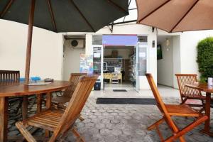 a patio with tables and chairs and an umbrella at RedDoorz Plus Syariah at Polamas Andalas in Padang