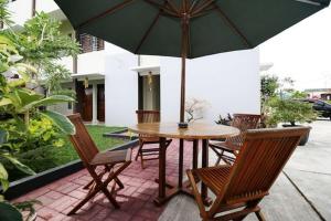 a table and chairs with an umbrella on a patio at RedDoorz Plus Syariah at Polamas Andalas in Padang