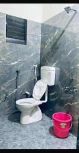 a bathroom with a toilet and a red bucket at Rajyog Resort in Dhule
