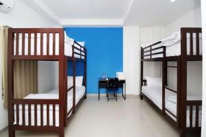 a room with three bunk beds and a desk at RedDoorz Plus Syariah at Polamas Andalas in Padang