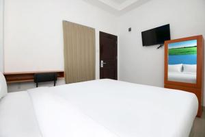 a bedroom with a large white bed and a mirror at RedDoorz Plus Syariah at Polamas Andalas in Padang