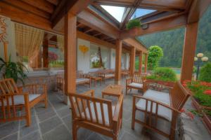 a patio with wooden chairs and tables andwindows at Hotel Panoramic in Auronzo di Cadore